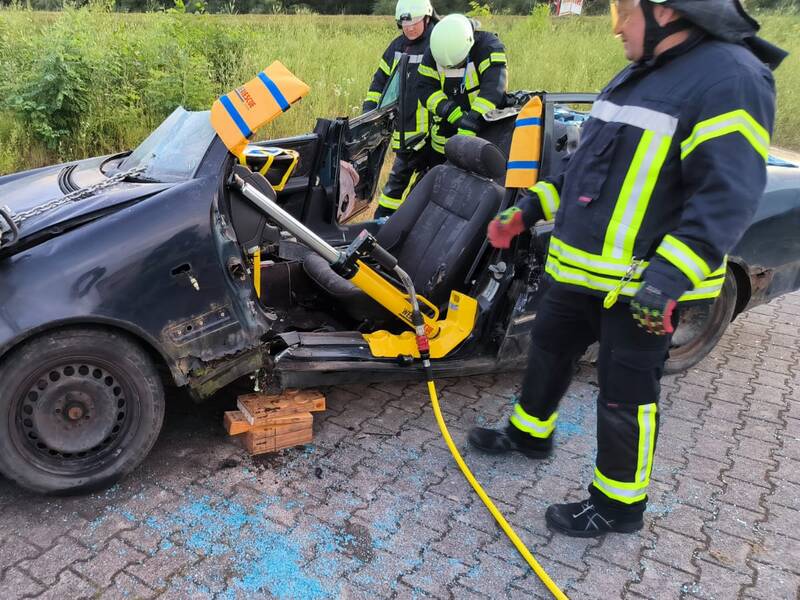 Mit hydraulischen Geräten zerschnittenes Fahrzeug an dem Feuerwehrleute arbeiten.