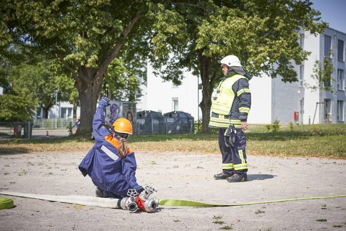 Ein Jugendfeuerwehrmädchen kniet am Verteiler und gibt den Befehl Wasser marsch.