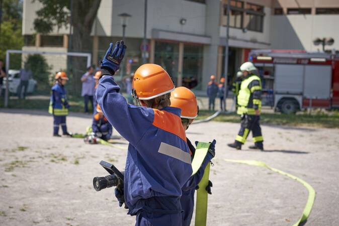 Ein Trupp der Jugendfeuerwehr mit einem Strahlrohr in der Hand.