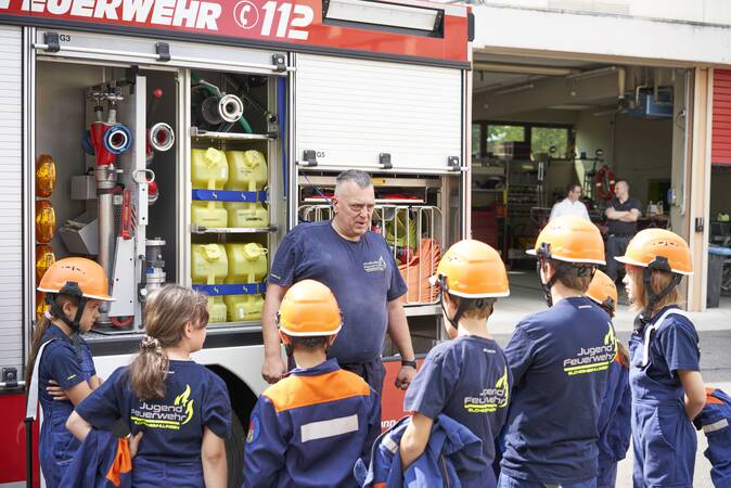 Besprechung einiger Jugendfeuerwehrmitglieder neben dem Hilfeleistungslöschgruppenfahrzeug zusammen mit einem Betreuer
