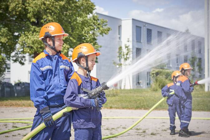 Zwei Jugendfeuerwehrkinder mit Strahlrohr bei der Wasserabgabe
